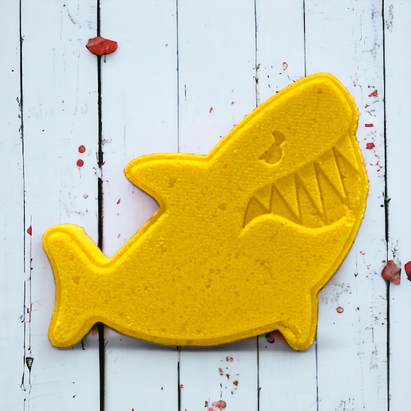 Shark fish bath bomb yellow on a wooded background. At calla Lily all natural cocoa butter coconut oil non toxic kid friendly